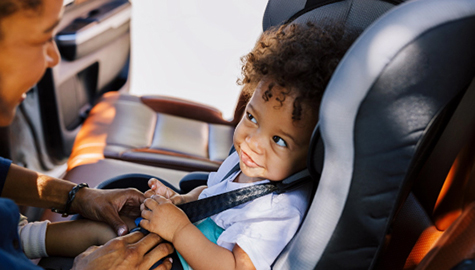 Toddler being buckled into car seat